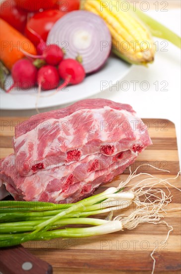 Chopping fresh pork ribs with vegetables and herbs ready to cook