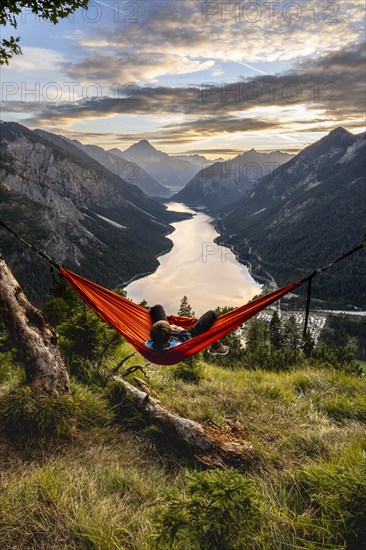 Young man sitting in an orange hammock