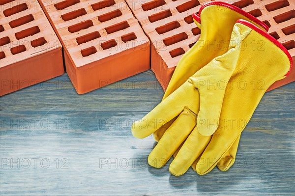 Building bricks yellow protective gloves on wooden board bricklaying concept