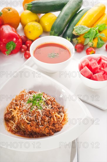 Italian classic spaghetti with bolognese sauce and fresh vegetables on background