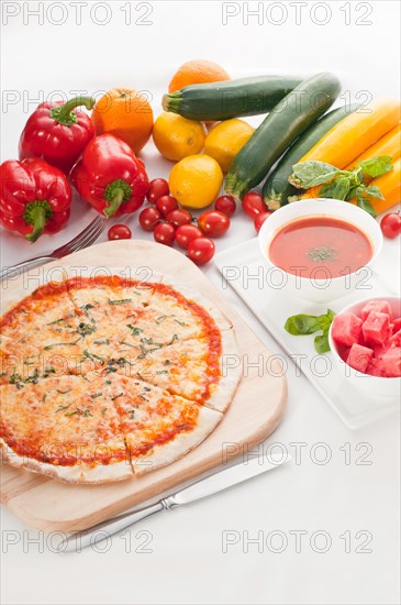 Italian original thin crust pizza Margherita with gazpacho soup and watermelon on side