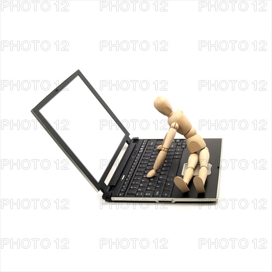 Wood mannequin sitting on a laptop isolated on white background