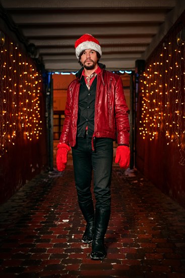 Man dressed as Santa Claus poses on a street decorated with garlands. New Year and Christmas concept. Mixed media