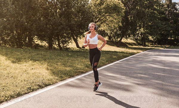 Fitness girl in sportswear runs through the evening sunny park. Healthy lifestyle. Mixed media