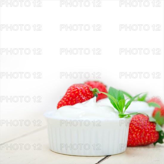 Organic Greek yogurt and strawberry over white rustic wood table