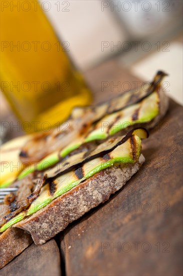 Grilled vegetables on rustic bread over wood table