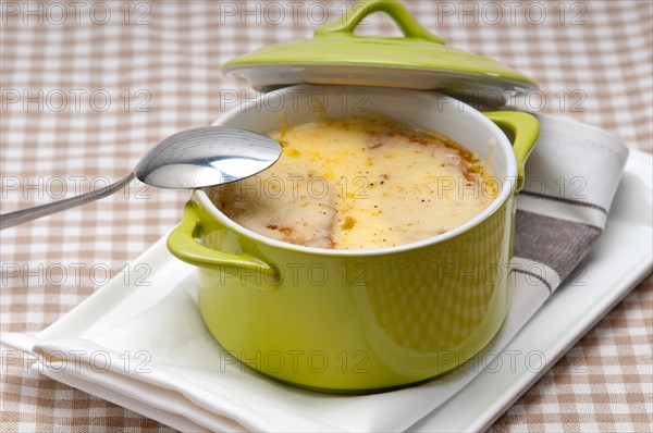 Onion soup on clay pot with melted cheese and bread on top