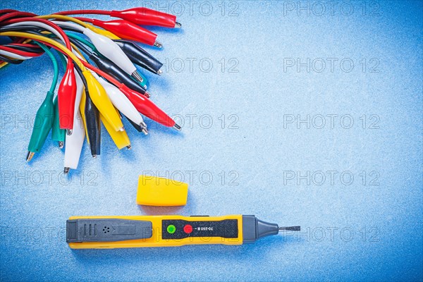 Electric tester indicator crocodile clip cables on blue background electricity concept