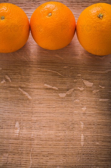 Three orange fruits on wooden table with organised copyspace