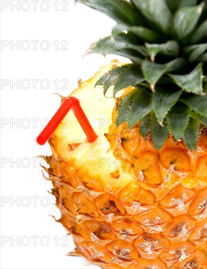 Ripe vivid pineapple with red straw over white background