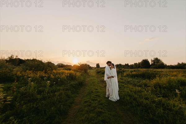 Loving couple of newlyweds at sunset in the field