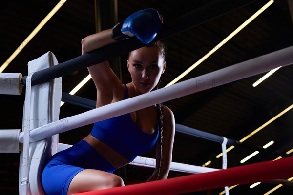 Beautiful and strong sportswoman posing in the corner of the ring. The concept of wrestling and boxing. Mixed media