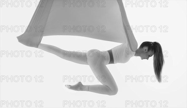 Image of a beautiful woman posing in a bright studio near the hammocks. The concept of airstretching. Fitness and sports