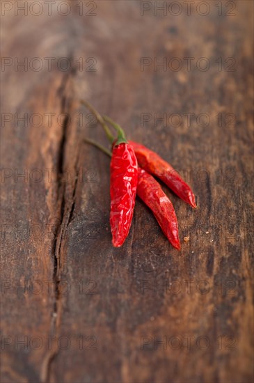 Dry red chili peppers over old wood table