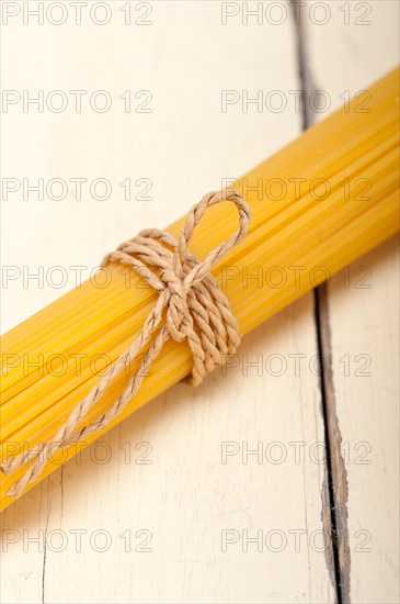 Italian pasta spaghetti tied with a rope on a rustic table