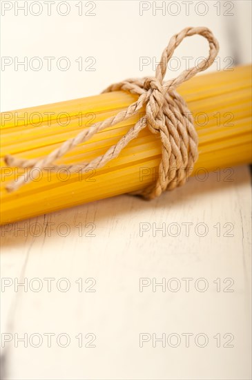 Italian pasta spaghetti tied with a rope on a rustic table