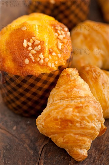 Fresh baked muffin and croissant mignon on old wood table