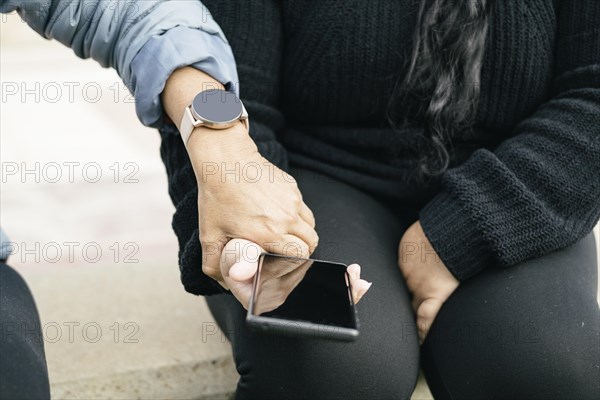 Two Spanish-Latino women with smartphones and smartwatches
