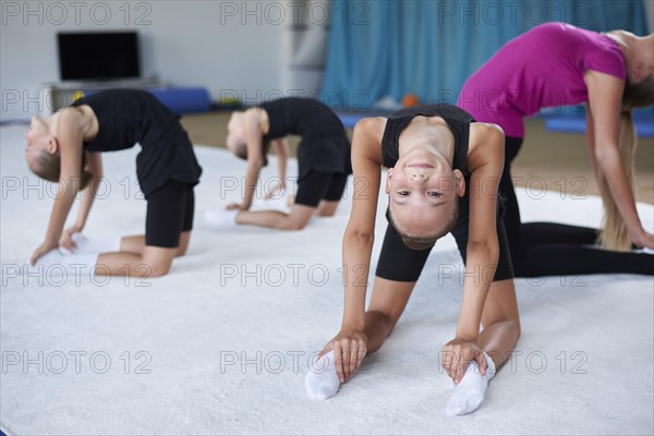 Training in the gym class. A group of children under the guidance of a coach perform exercises. Gymnastics concept. Mixed media