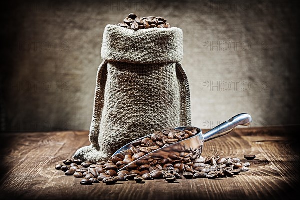 Scoop and sack with coffee beans on vintage wood table