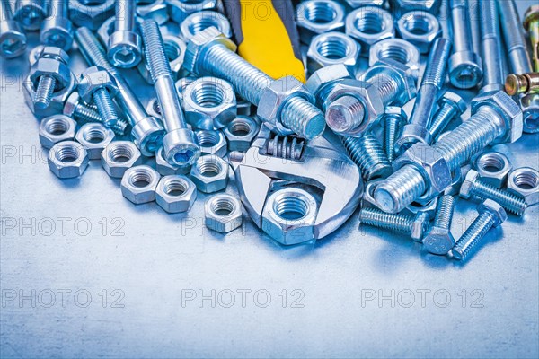 Adjustable key stainless bolt details and nuts on metallic background construction concept