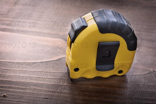 Yellow tape measure on vintage wooden board construction concept