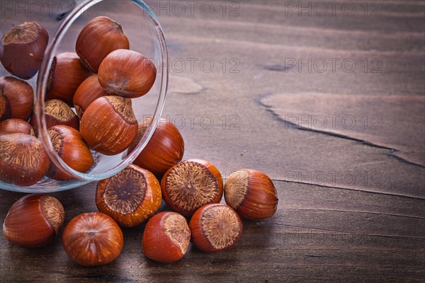Horizontal version Stack of hazelnuts in glass bowl on vintage wooden board Food and drink still life
