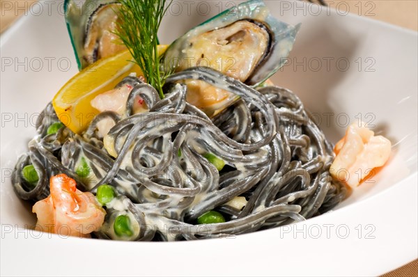 Fresh seafood black squid ink coulored spaghetti pasta tipycal italian food