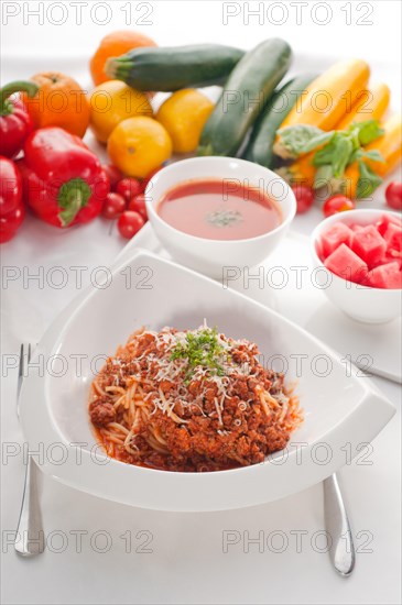 Italian classic spaghetti with bolognese sauce and fresh vegetables on background