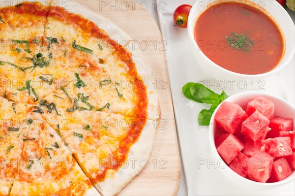 Italian original thin crust pizza Margherita with gazpacho soup and watermelon on side