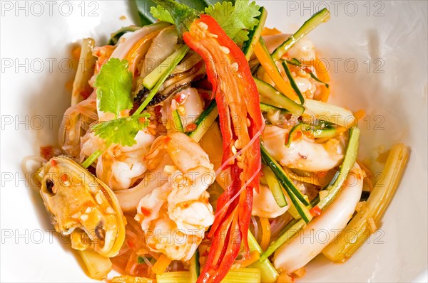 Fresh seafood thai style salad with glass noodles on a bowl close up