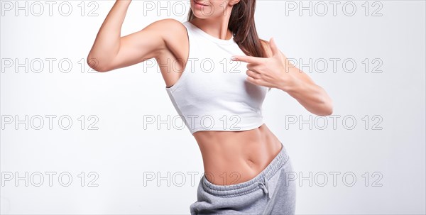 No name portrait. Young white fitness woman wearing sportswear standing over white wall background. Fitness concept. Mixed media