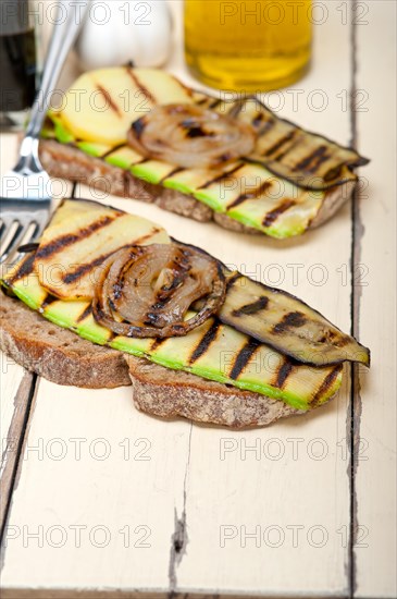 Grilled vegetables on rustic bread over wood table