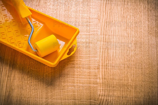 Copyspace picture yellow paint roller in tin on wooden board