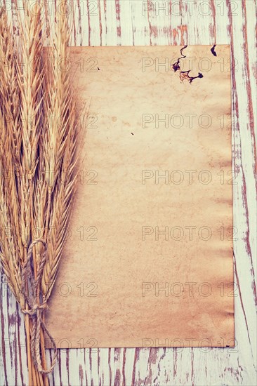Copyspace background bunch of wheat ears on vintage blanc paper and old wooden board instagram style food and drink concept