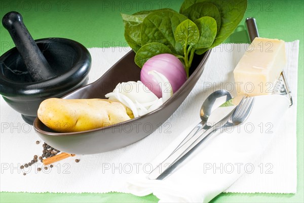 Bowl of fresh vegetable with spice and mortar beside