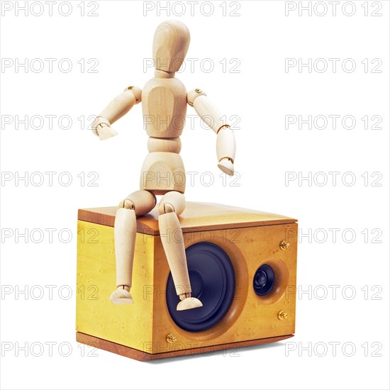 Wood mannequin sitting on a speaker isolated on white background