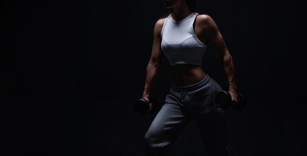 Athletic fitness woman posing in the studio on a dark background. Photo of an attractive woman in fashionable sportswear. Sports and healthy lifestyle. Mixed media