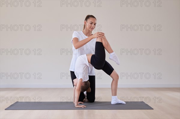 Beautiful female teacher helps a little girl stretch in a gymnastics class. The concept of education