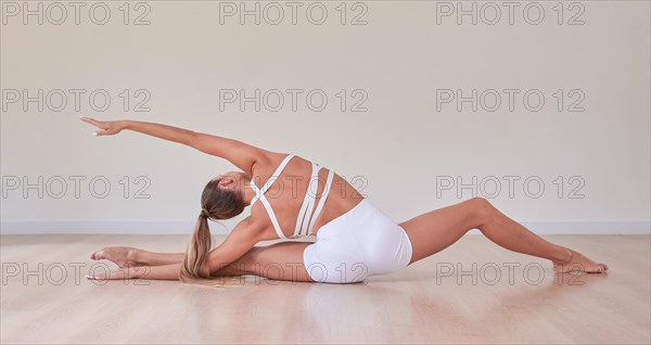 Flexible woman is training in a light studio. The concept of gymnastics