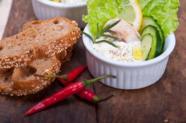 Fresh organic garlic cheese dip salad on a rustic table with bread