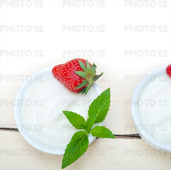 Organic Greek yogurt and strawberry over white rustic wood table