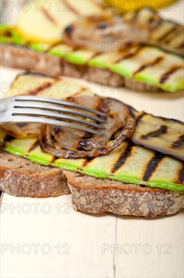 Grilled vegetables on rustic bread over wood table