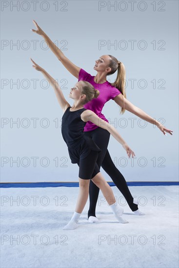 Training in the gym class. A little girl under the guidance of a trainer performs exercises. Gymnastics concept. Mixed media