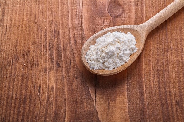 Wooden spoon with flour on old wooden board horizontal version