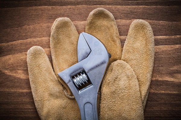 Adjustable spanner leather protective gloves on wooden board construction concept