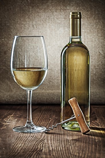 Bottle and glass with white wine and corcksrew