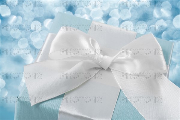 Top view of blue gift box with white ribbon on blurred background