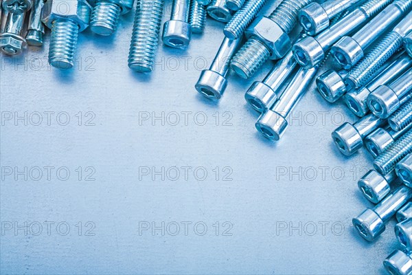 Heap of metal threaded hexagon bolts on metallic background repairing concept