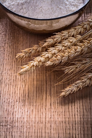 Wheat ears and bowl with flour on wooden board Food and drink Still life